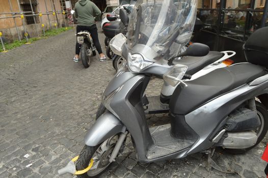 Parked motorcycles on the cobblestone pavement of Rome, traditional Italian transport.