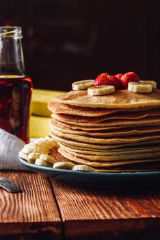 Homemade Pancakes with Maple Syrup, Strawberries and Banana. Vertical orientation.