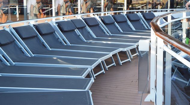 Empty sunbeds lounge chairs for relaxing on the open deck of a cruise ship.