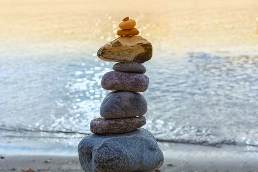 Stones stacked on top of each other on the beach with sea view in the background
