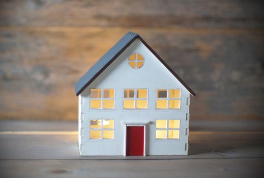 Model house with lights on inside over a wooden background