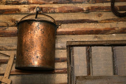 Old copper pail on wooden wall inside barn