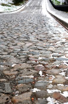 Old empty cobblestone roadway with snow in provincial town 