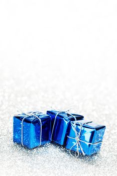 Decorative blue boxes with holiday gifts on shiny glitter background