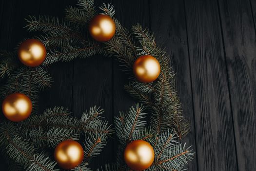 Christmas or New Year toy decorations golden ball and fur tree branch rustic on wooden background, top view, copy space