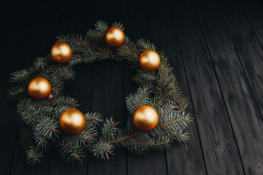 Christmas or New Year toy decorations golden ball and fur tree branch rustic on wooden background, top view, copy space