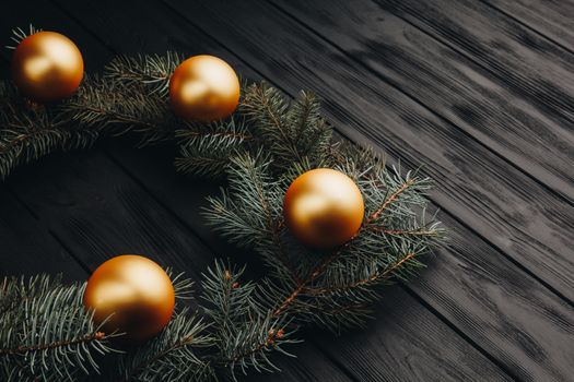 Christmas or New Year toy decorations golden ball and fur tree branch rustic on wooden background, top view, copy space