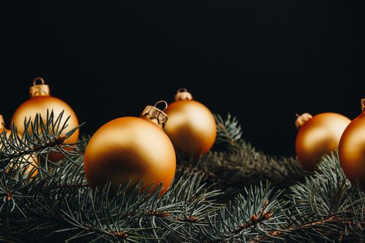 Christmas or New Year toy decorations golden ball and fur tree branch rustic on wooden background, top view, copy space