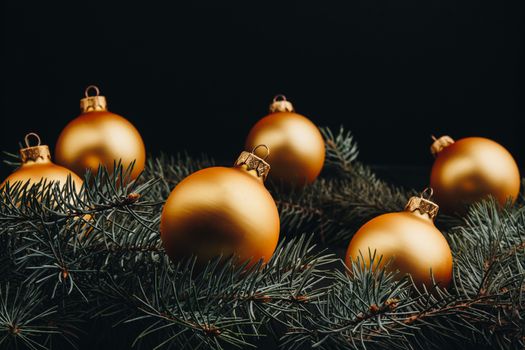 Christmas or New Year toy decorations golden ball and fur tree branch rustic on wooden background, top view, copy space