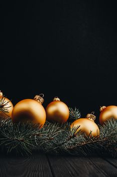 Christmas or New Year toy decorations golden ball and fur tree branch rustic on wooden background, top view, copy space