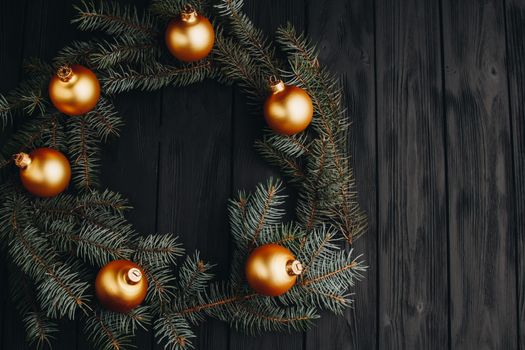 Christmas or New Year toy decorations golden ball and fur tree branch rustic on wooden background, top view, copy space