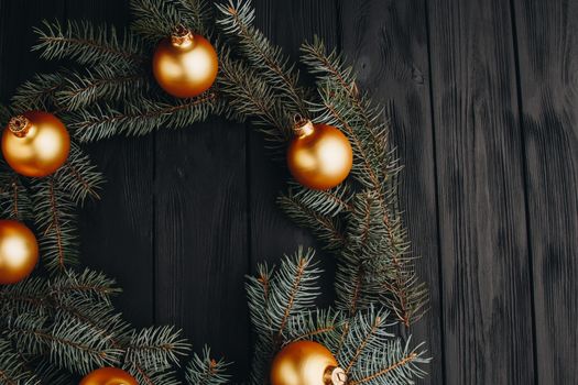 Christmas or New Year toy decorations golden ball and fur tree branch rustic on wooden background, top view, copy space