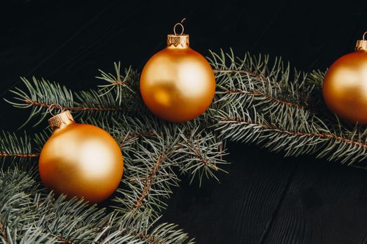 Christmas or New Year toy decorations golden ball and fur tree branch rustic on wooden background, top view, copy space