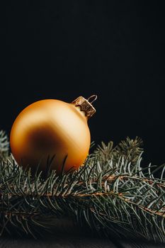 Christmas or New Year toy decorations golden ball and fur tree branch rustic on wooden background, top view, copy space