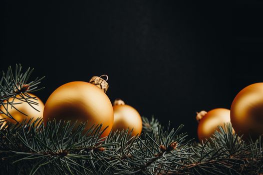 Christmas or New Year toy decorations golden ball and fur tree branch rustic on wooden background, top view, copy space