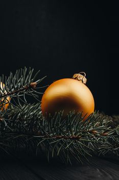 Christmas or New Year toy decorations golden ball and fur tree branch rustic on wooden background, top view, copy space