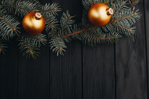 Christmas or New Year toy decorations golden ball and fur tree branch rustic on wooden background, top view, copy space