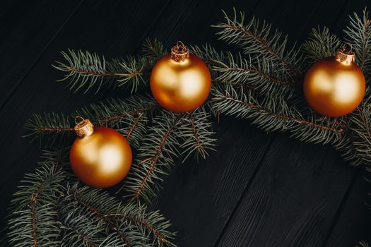 Christmas or New Year toy decorations golden ball and fur tree branch rustic on wooden background, top view, copy space