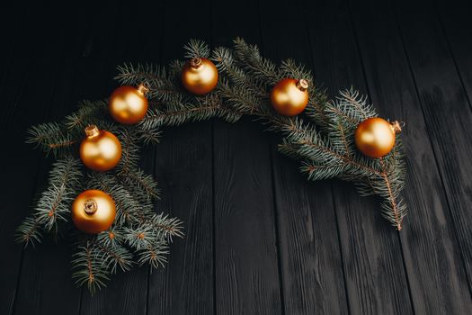 Christmas or New Year toy decorations golden ball and fur tree branch rustic on wooden background, top view, copy space