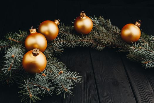 Christmas or New Year toy decorations golden ball and fur tree branch rustic on wooden background, top view, copy space