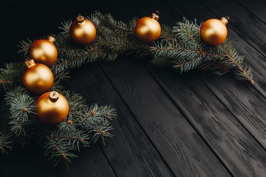 Christmas or New Year toy decorations golden ball and fur tree branch rustic on wooden background, top view, copy space