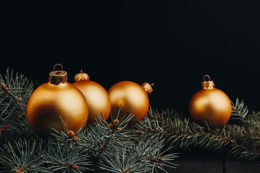 Christmas or New Year toy decorations golden ball and fur tree branch rustic on wooden background, top view, copy space