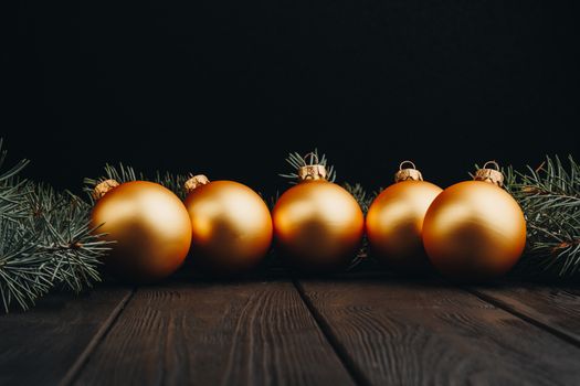 Christmas or New Year toy decorations golden ball and fur tree branch rustic on wooden background, top view, copy space