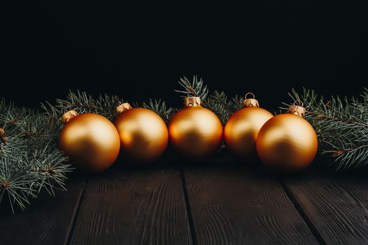 Christmas or New Year toy decorations golden ball and fur tree branch rustic on wooden background, top view, copy space