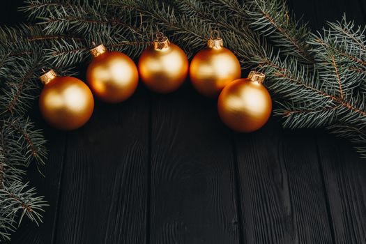 Christmas or New Year toy decorations golden ball and fur tree branch rustic on wooden background, top view, copy space