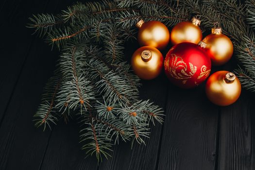 Christmas or New Year toy decorations golden ball and fur tree branch rustic on wooden background, top view, copy space