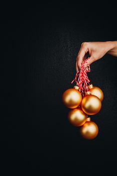 golden Christmas balls in hand isolated on black background. new year card