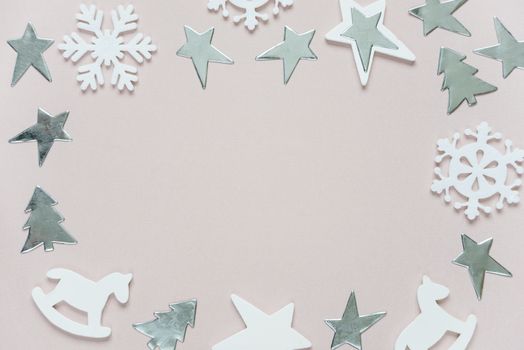 Christmas frame composed of white christmas decoration: snowflakes, stars, Christmas trees and toy; rocking horse on pink background. Flat lay composition for greeting card, websites, social media, magazines,  bloggers, artists etc.