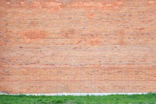 Large wall of red brick with a border of green grass