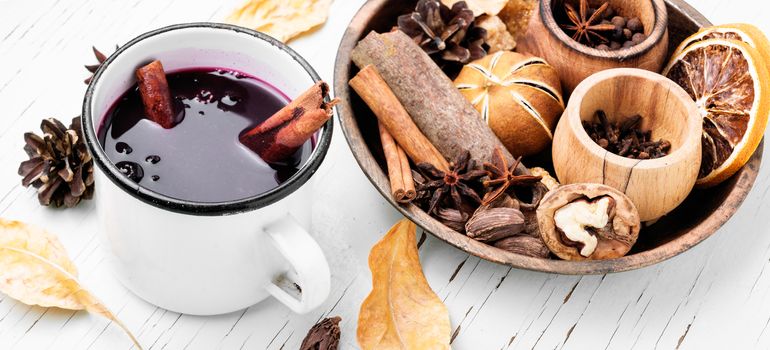 Mulled wine hot drink and spices in rustic mugs on rustic background