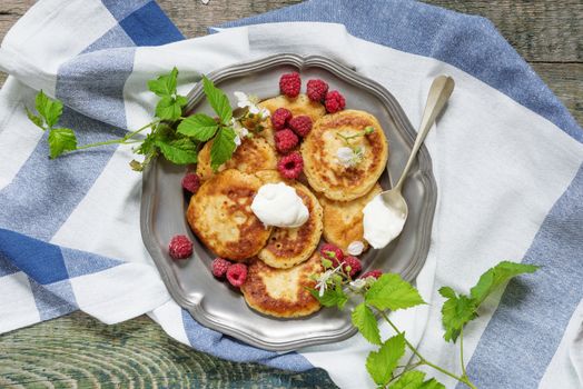 Breakfast of pancakes with sour cream and berries ripe raspberry, top view