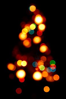 Bokeh silhouette of Christmas tree on black background