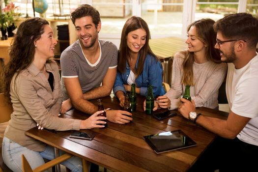 A group of friends at the bar drinking a beer 