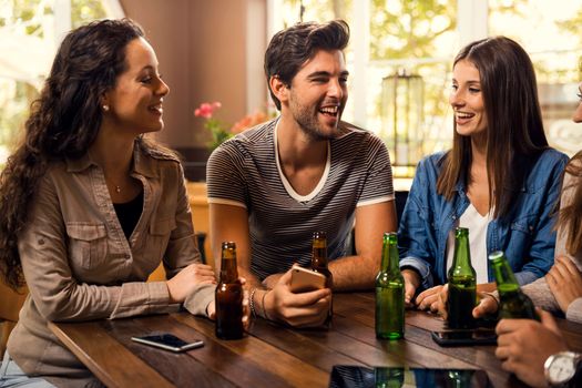 A group of friends at the bar drinking a beer 