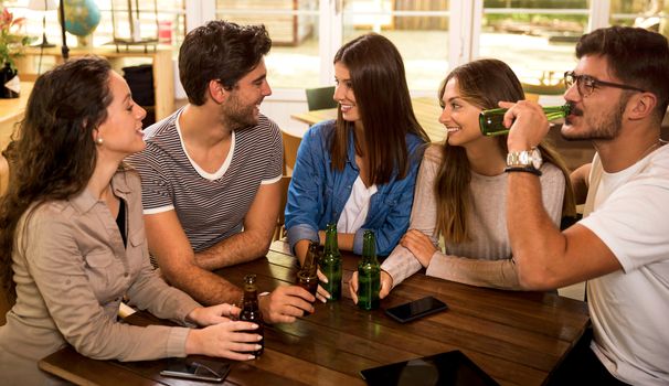 A group of friends at the bar drinking a beer 