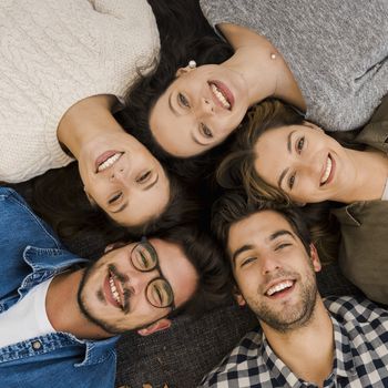 Top view of a group of friends lying on floor and looking at camera