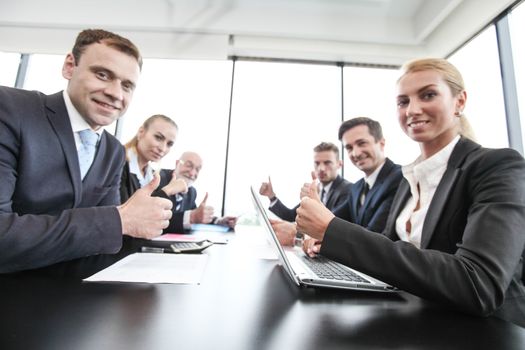 Mixed group of people in business meeting working with documents and computers showing thumbs up