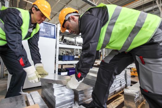 Workers taking aluminium billet at CNC machine shop