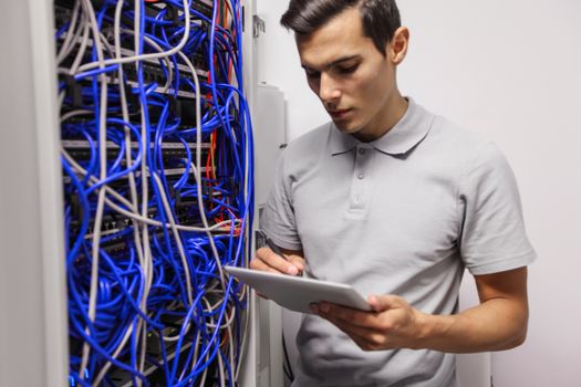 Young engeneer man in network server room with digital tablet