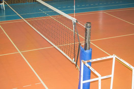 Empty sports hall with a stretched volleyball net and a tower for the judge.