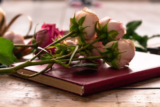 On the wooden surface laid out tools for flower bouquets: scissors, roses, colored ribbon, roses.