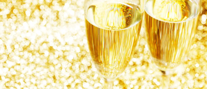 Pair of champagne flutes on shiny glitter background