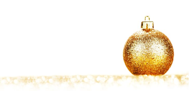 Beautiful golden christmas ball on abstract glitter background close-up