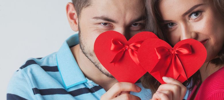 Young couple celebrating Valentine day holding paper heart cards