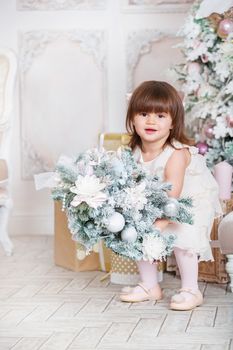 Merry Christmas and Happy Holidays! Cute funny little child girl is decorating the Christmas tree indoors