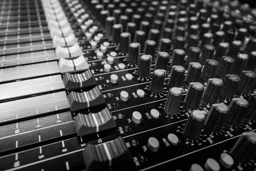 Low level view of Faders on a Professional Audio Sound Mixing Console at music festival, black desk and white Faders